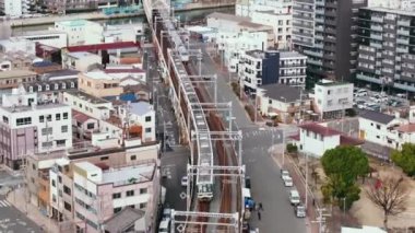Şehir merkezinden geçen yüksek demiryolu hattında birbirinin yanından geçen tren birimlerinin havadan görüntüsü. Osaka, Japonya.