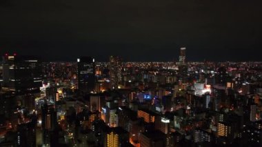 Şehir merkezindeki binaların havadan yükselen görüntüleri. Şehrin gece manzarasını hayret verici bir şekilde gösteriyor. Osaka, Japonya.