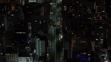 Gece şehrinin üzerinde uç. Şehirdeki caddelerden geçen araçların yüksek açılı görüntüsü. Osaka, Japonya.