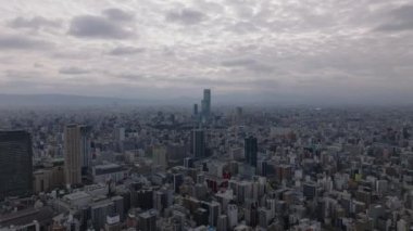 İleri, büyük şehrin üzerinde uçar. Bulutlu gökyüzünün altındaki Metropolis 'in hava panoramik görüntüleri. Kasaba gelişiminin yoğunluğu yüksek. Osaka, Japonya.
