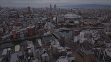 Şehir merkezinin üzerinde ilerliyorlar. Osaka Dome Beyzbol Stadyumu 'nun yanındaki nehrin üzerindeki geniş yol köprüsü. Sabah metropolünün hava görüntüsü. Osaka, Japonya.