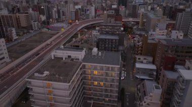 Şehir merkezindeki binaların ve yüksek şeritli yollarda giden arabaların yüksek açılı görüntüsü. Yukari egilmek sabah sehrini ortaya çikarir. Osaka, Japonya.