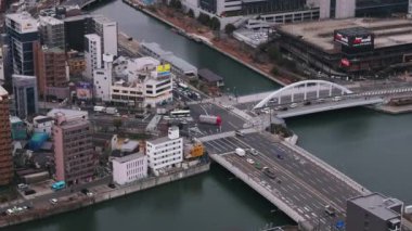 Şehir merkezindeki kavşaktan geçen araçların hava görüntüleri. Şehirdeki nehir üzerindeki yol köprüleri. Osaka, Japonya.
