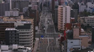 Geniş caddenin üzerinde büyük şehirlerdeki yüksek modern konut binalarıyla çevrili ileriye doğru uçar. Osaka, Japonya.