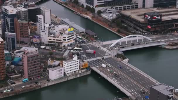 从空中拍摄通过市区交叉口的车辆 城市里河上的公路桥 日本大阪 — 图库视频影像