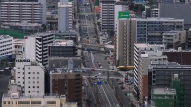 Şehir merkezindeki binalarla çevrili çok şeritli caddenin havadan görünüşü. Osaka, Japonya.
