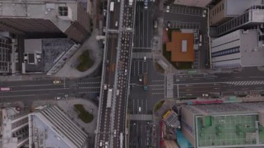 Şehirdeki çok şeritli caddedeki trafiğin en alt görüntüsü. Ana yol yüksek binalarla çevrili. Osaka, Japonya.