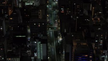 Forwardlar düz caddenin üzerinden uçuyor. Şehir merkezinde yüksek binalarla dolu. Gece şehri sahnesi. Osaka, Japonya.