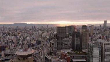 Metropolis 'in gökdelenli panoramik görüntüleri. Yüksek binaları ve işlek caddeleri var. Arka planda gündoğumu olan sabah sahnesi. Osaka, Japonya.