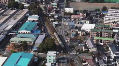Tren durağına yaklaşan yüksek açılı tren görüntüsü. Şehrin banliyölerindeki toplu taşıma araçlarının hava görüntüsü. Japonya.
