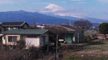 Şehrin dışındaki aile evlerinin havadan yükselen görüntüleri. Arkasında kar olan Fuji Dağı 'nın inanılmaz yüksek zirvesi. Japonya.