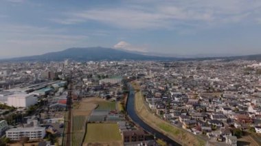 Kentsel yerleşim bölgesi ve Fujisan karla kaplı dağıyla şehrin panoramik manzarası. Görüntüler iniyor. Japonya.