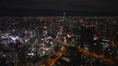 Gece Metropolis 'in üstünde uç. Büyük şehirde bir kasaba inşaatı var. Popüler gece hayatı parlayan bölge Dotonbori. Osaka, Japonya.