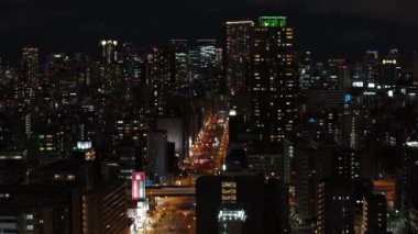 Gece büyük şehrin havadan yükselen görüntüsü. Şehir merkezindeki uzun binalar ve sokaklar. Osaka, Japonya.
