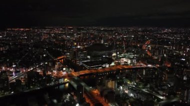 Gece metropolünün havadan panoramik görüntüsü. Büyük şehirde binalar ve aydınlık sokaklar. Osaka, Japonya.