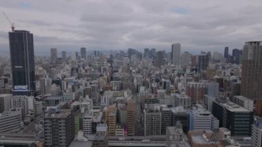 Bulutlu bir günde metropolün üzerinde ilerliyorlar. Metropolis 'in gökdelenli panoramik manzarası. Osaka, Japonya.