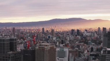 Sabahleyin Metropolis 'in üstünde uç. Gökyüzündeki bulutlarda parlayan güneş ışınlarının romantik görüntüsü. Osaka, Japonya.