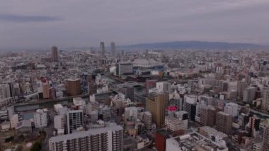 Metropolis 'in hava panoramik görüntüleri. Büyük şehirde yoğun şehir gelişimi ve nehirler. Beyzbol stadyumu Osaka Dome. Osaka, Japonya.