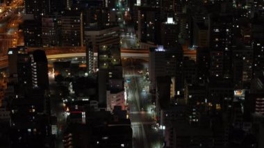 Gece şehir sokaklarında düşük trafiğin yüksek açılı görüntüsü. Konut arazisindeki çok katlı binaları ortaya çıkarmak için yukarı doğru eğil. Osaka, Japonya.