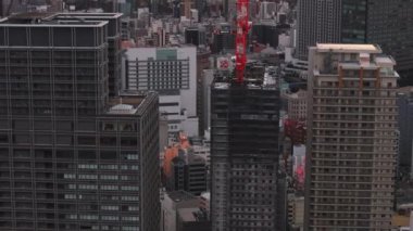 Şehirdeki modern yüksek binaların etrafında uçmak. Eğim, renkli gündoğumuna karşı şehir manzarasını ortaya çıkarır. Osaka, Japonya.