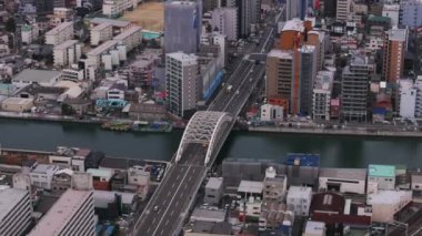 Şehirdeki dar nehir boyunca uzanan çok şeritli yol köprüsünün hava kaydırağı ve yan görüntüsü. Arch Köprüsü 'nden geçen arabalar. Osaka, Japonya.