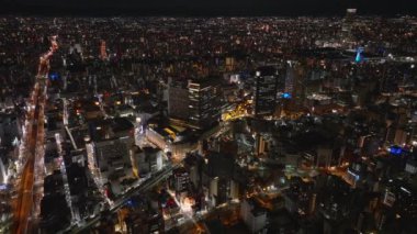 Şehir merkezindeki yüksek binaların hava kaydırak ve pan görüntüleri. Gece Metropolis 'in üstünde uç. Osaka, Japonya.