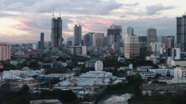 Düşük endüstriyel yapıların ve arka plandaki modern kentsel ilçenin hava kaydırak ve pan görüntüleri. Gökyüzünde bulutlar. Manila, Filipinler.