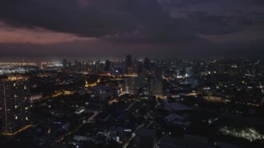 Akşamları şehrin güzel hava manzarası. Sokaklar ve binalar gece aydınlanıyor. Gökyüzünü bulutlarla renklendirin. Manila, Filipinler.
