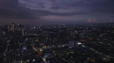 Alacakaranlıktaki büyük şehrin havadan panoramik görüntüsü. Gece Metropolis 'in üzerinde uç. Karanlık gökyüzünde bulutlar. Manila, Filipinler.