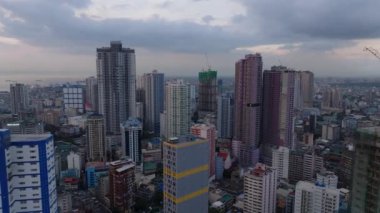Şehir merkezindeki modern yüksek binaların havadan yükselen görüntüleri. Alacakaranlıktaki Metropolis 'in panoramik manzarası. Manila, Filipinler.
