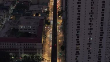 Akşam kentinde kalabalık caddenin üzerinde ilerliyorlar. Yüksek binalarla çevrili aydınlık caddelerde giden araçlar. Manila, Filipinler.