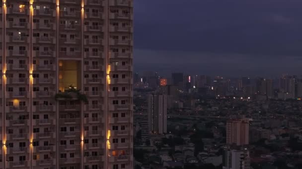ファサードを飾るライト付きの高層住宅ビルの空中上昇映像 バックグラウンドの夜景 マニラ フィリピン — ストック動画
