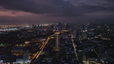 Metropolis 'in güzel akşam panoramik manzarası. Aydınlatılmış sokaklar ve büyük şehirlerdeki binalar. Deniz kıyısındaki liman mesafesi. Manila, Filipinler.