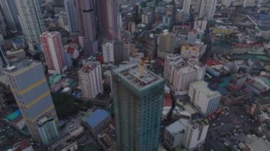 Modern bina inşaatının tepesinde vincin etrafında uçmak. Şehrin gelişimine yüksek açılı bir bakış açısı. Manila, Filipinler.