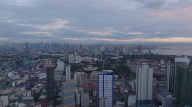 Gün batımında Metropolis 'in havadan panoramik görüntüsü. Yüksek apartman binasının tersten görünümü. Manila, Filipinler.