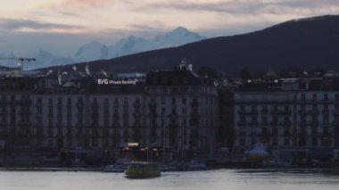 Su yüzeyindeki turist teknesinin havadan görünüşü, göl kıyısındaki saraylar ve arka planda kar yağışı Mont Blanc kalabalığı. Cenevre, İsviçre.