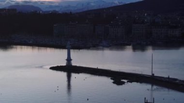 Cenevre Gölü 'nün sabah görüntüsü. Phare des Paquis deniz fenerinin silueti su yüzeyine karşı. Bulutlu gün doğumu gökyüzü. Cenevre, İsviçre.