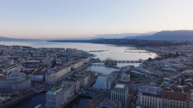 İleri, Sabah Şehri 'nin üzerinde uçar. Nehrin üzerindeki köprüler büyük gölden ve kentsel bölgelerdeki binalardan akıyor. Cenevre, İsviçre.