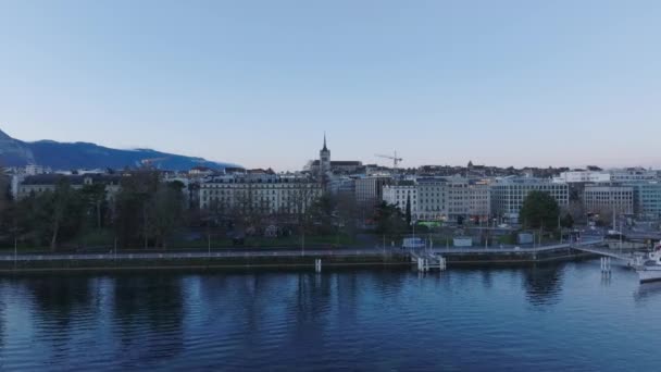 前进在湖面上方飞行 市区多层建筑物的空中景观 圣皮埃尔大教堂塔楼 瑞士日内瓦 — 图库视频影像