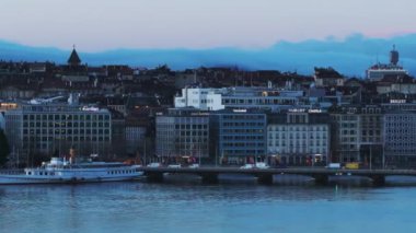Araçlar su üzerinde yol köprüsünden geçiyor. Sabah kentinde rıhtımdaki binalar. Yolcu gemisi ortaya çıkıyor. Cenevre, İsviçre.