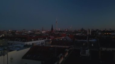 Şehir merkezindeki çatıların üzerinden uç. Metropolis 'teki yoğun şehir gelişimi. Kilise kulesi ve popüler Fernsehturm 'la akşam manzarası. Berlin, Almanya.