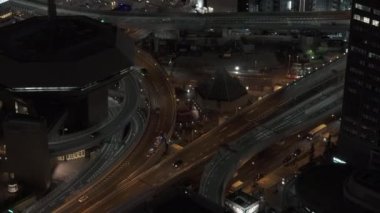 Şehirdeki ulaşım altyapısının hava görüntüleri. Gece yarısı, şehir merkezindeki çok katlı kavşaktan geçen araçlar. Osaka, Japonya.