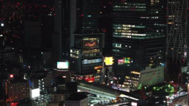 Geceleri şehir merkezindeki modern binaların manzarası yükseliyor. Işıklı pencereli yüksek binalar. Tokyo, Japonya.