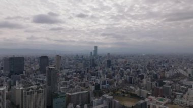 Modern yüksek binalarla şehir manzarasının havadan yükselen görüntüsü. Büyük şehrin üzerindeki bulutlu gökyüzü. Osaka, Japonya.