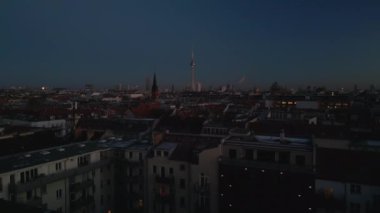 Alacakaranlıktaki şehir manzarası. Şehir merkezindeki turistik yerler. Geriye doğru, gazla ısıtılan binanın bacasından çıkan dumanı ortaya çıkardı. Berlin, Almanya.