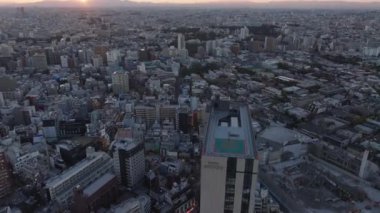 Şehir merkezinin üzerinden uçun, alacakaranlıkta büyük şehirde sokaklar ve binalar. Yüksek katlı otel, yerleşim yerlerinin üstünde. Tokyo, Japonya.
