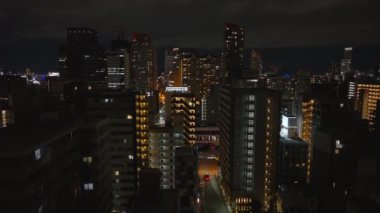 Metropolis 'teki yerleşim yerlerindeki çok katlı apartmanların hava yükselen görüntüleri. Geceleri yüksek katlı modern yapılar. Osaka, Japonya.
