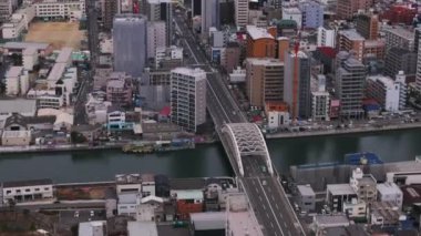 Şehirdeki nehir üzerindeki yüksek açılı köprü manzarası. Şehir merkezindeki çok katlı apartman binaları. Osaka, Japonya.