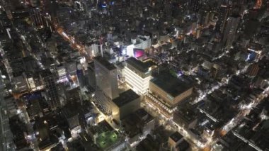 Şehrin gelişimine yüksek açılı bir bakış açısı. Sokak şebekesi ve çok katlı binaları olan şehir merkezi. Gece şehrinin üzerinde uç. Osaka, Japonya.