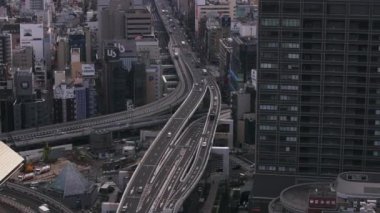 Şehir gelişimiyle çevrili çok şeritli cadde ve yol kesişiminin hava görüntüleri. Şehirden geçen araçlar. Osaka, Japonya.